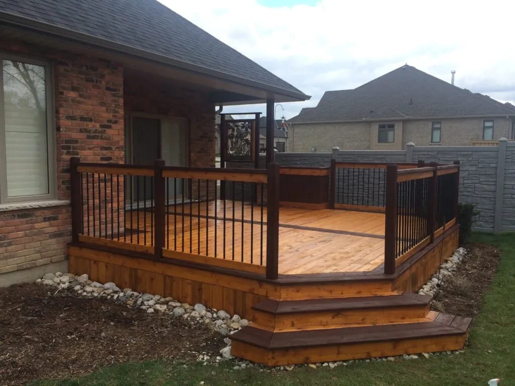 Covered deck stained cedar beside a brick home