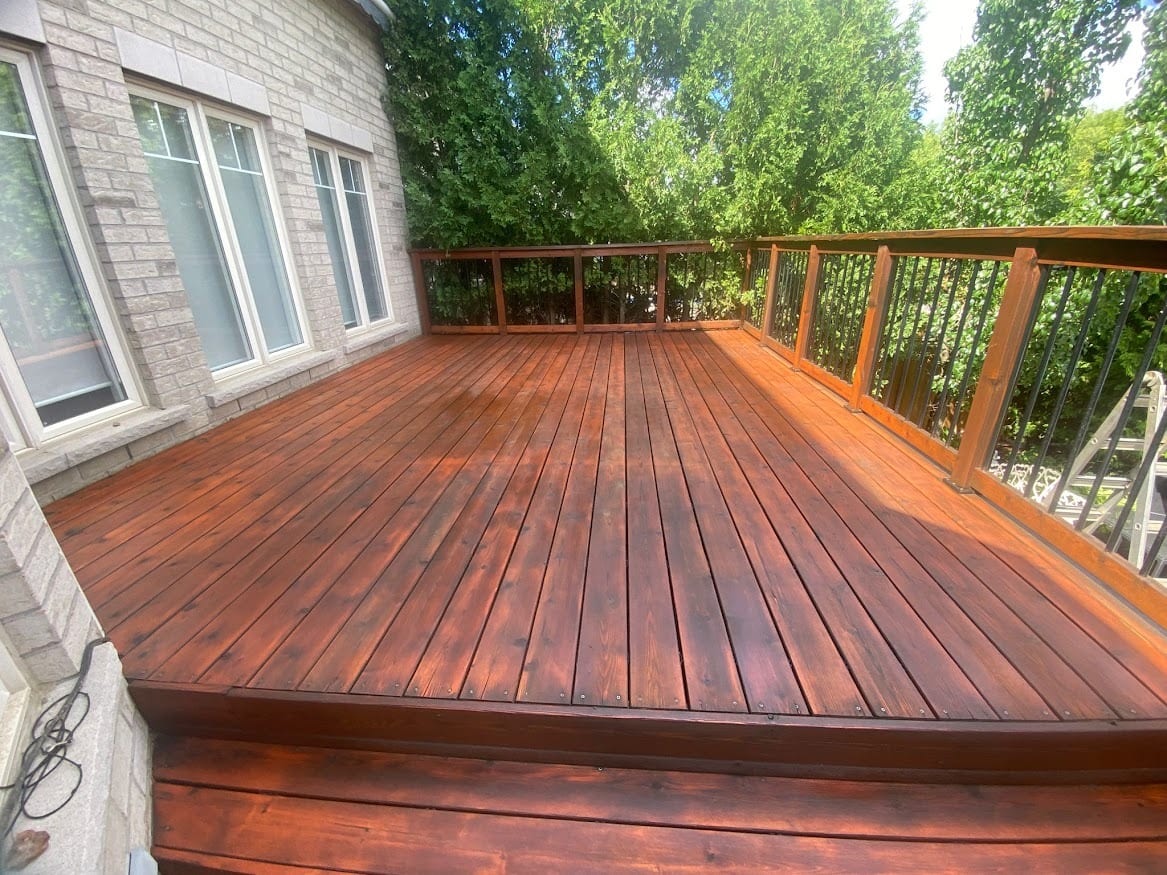 Freshly stained deck at a brick two-storey home