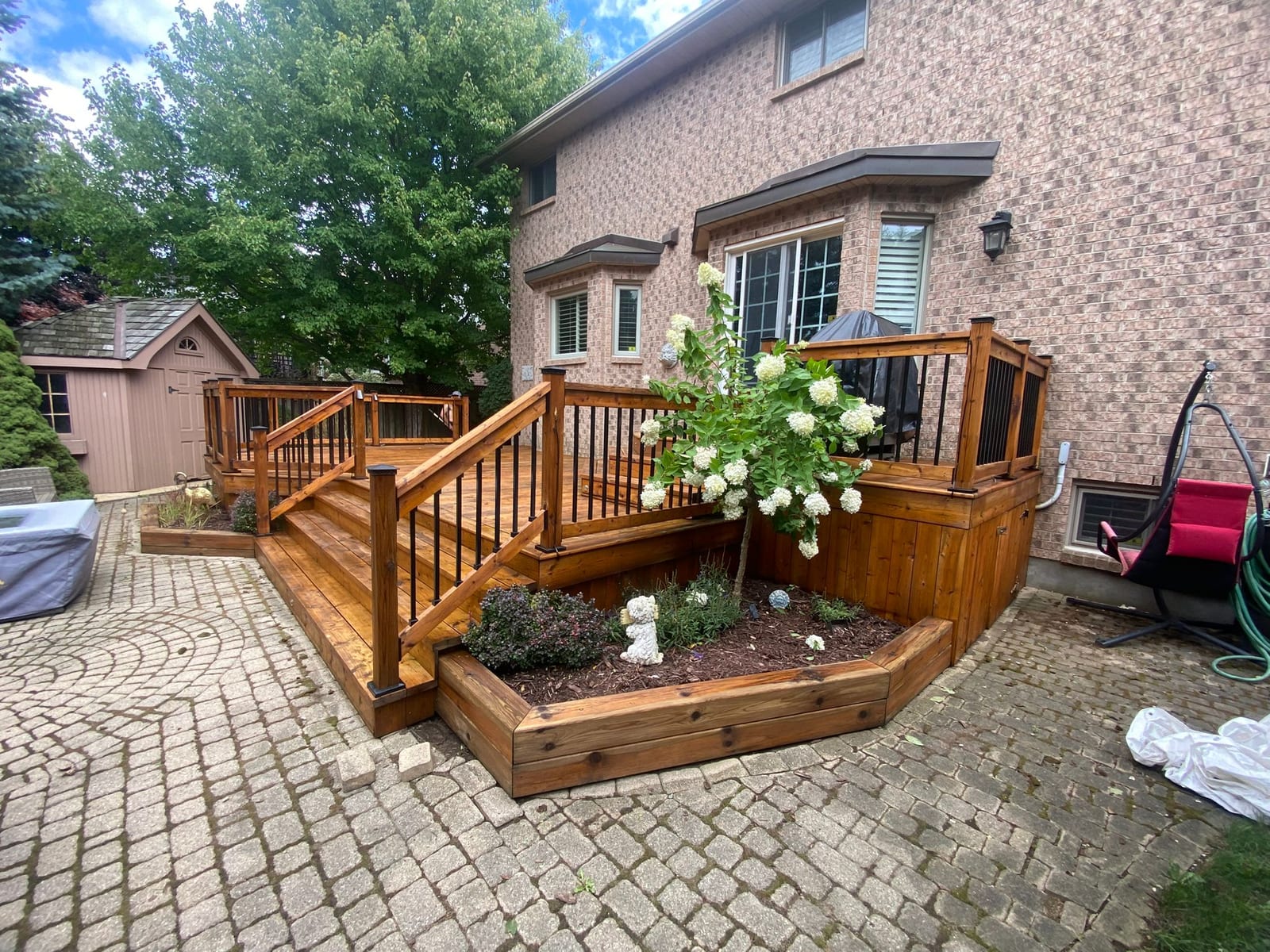 Restored and stained backyard deck with planters behind a brick home in Kitchener, by Restore My Deck