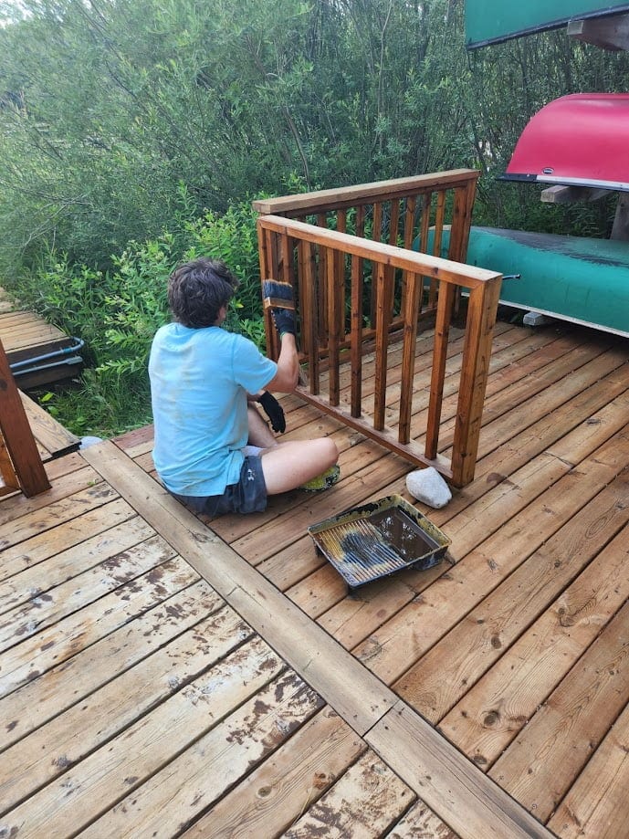 Restore My Deck technician hand-sanding a deck railing before staining